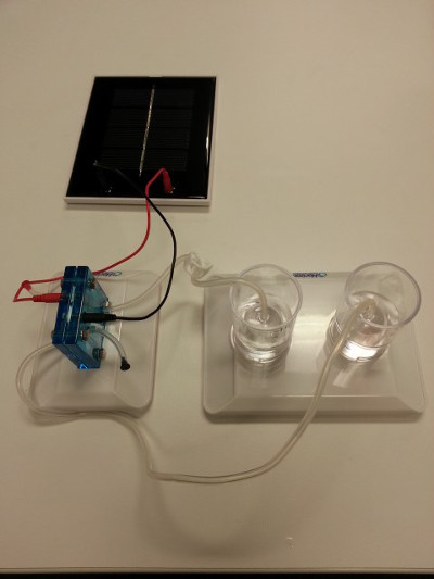 Hydrogen electrolysis setup with solar panel, demonstrating water splitting and gas collection process.