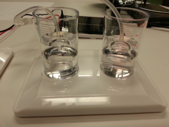 Electrolysis process diagram showing electrode setup in dual-beaker system for chemical separation.
