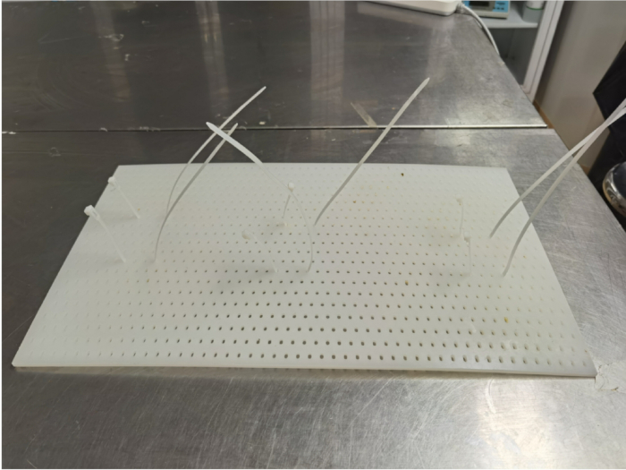 Static equilibrium diagram with rods on pegboard, illustrating force principles and balance.