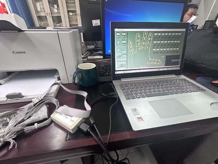 figure-protocol-11 Hand biometric system, laptop screen shows fingerprint analysis software; setup on office desk.